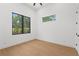 Minimalist bedroom with sleek wood floors, two large windows offering views of the surrounding greenery, and white walls at 2632 Hawthorne St, Sarasota, FL 34239