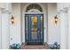 Elegant front entryway with a leaded glass door, columns, sconces, and planters with blue hydrangeas at 3415 162Nd E Ave, Parrish, FL 34219