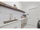 Chic laundry room featuring sleek white cabinetry, stunning gold fixtures, and a floating wooden shelf for stylish storage at 3415 162Nd E Ave, Parrish, FL 34219