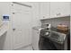 Laundry room showcasing a modern washer and dryer set with white cabinets and easy access to the home security system at 3415 162Nd E Ave, Parrish, FL 34219