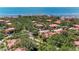 An aerial view of a charming community with lush trees, red roofs, and a view of the beautiful blue ocean in the background at 3803 Sun Eagle Ln # 203, Bradenton, FL 34210