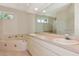 Bathroom featuring double sinks and a tub, with a glass block accent wall and tiled floors at 4092 Green Tree Ave, Sarasota, FL 34233