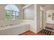 Elegant bathroom with a large tub, white tile, hardwood floors, and natural light from an arched window at 4691 Las Brisas Ln, Sarasota, FL 34238