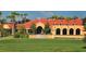 Clubhouse exterior with red tile roof, archways, lush landscaping, and golf course putting green at 4691 Las Brisas Ln, Sarasota, FL 34238