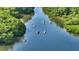 Aerial shot of kayakers paddling through a serene, tree-lined river, showcasing the natural beauty of the area at 4800 Gulf Of Mexico Dr # 205, Longboat Key, FL 34228