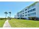 Beautiful condo building with lush green lawn, tropical trees and convenient covered parking at 4800 Gulf Of Mexico Dr # 205, Longboat Key, FL 34228