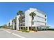 Low angle of the white beach condos with palm trees, blue skies, and an inviting coastal allure at 4800 Gulf Of Mexico Dr # 205, Longboat Key, FL 34228