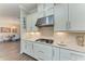Modern kitchen featuring stainless steel hood, granite countertops, white cabinets, and stylish backsplash at 4908 Tivoli Run, Bradenton, FL 34211
