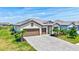 Beautifully landscaped home with a three-car garage and a paved driveway under a sunny blue sky at 4975 Seafoam Trl, Bradenton, FL 34211