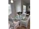 Dining area features white wicker chairs around glass table and wood flooring at 5741 Soldier Cir # 202, Sarasota, FL 34233