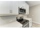 Close-up of the kitchen featuring stainless steel appliances, white quartz countertop, and white cabinets at 5957 Amberly Dr, Bradenton, FL 34208