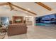 Open-concept living room with exposed wood beams, bar, and large sliding doors to lanai at 621 Ivanhoe Ln, Holmes Beach, FL 34217
