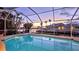 Pool and spa at dusk, surrounded by a screened enclosure and waterfront views at 621 Ivanhoe Ln, Holmes Beach, FL 34217