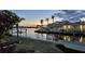 Beautiful waterfront property featuring a private dock, lush landscaping, and serene canal views at dusk at 621 Ivanhoe Ln, Holmes Beach, FL 34217