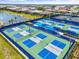 Aerial view of the community's well-maintained pickleball courts, set against a backdrop of lush greenery and lake at 6248 Fish Eagle Ct, Nokomis, FL 34275