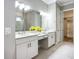 Bright bathroom featuring double vanity sinks, white cabinetry, and a view of the walk-in closet at 6290 Mesa Gln, Bradenton, FL 34203
