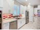 Kitchen boasts white cabinets, stainless steel appliances, and a red and white backsplash at 6290 Mesa Gln, Bradenton, FL 34203