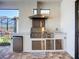 Covered outdoor kitchen has stainless steel appliances, grill, refrigerator, marble countertop, and sink at 6290 Mesa Gln, Bradenton, FL 34203