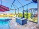 Screened in pool has attached spa and a fire pit, with seating and an umbrella at 6290 Mesa Gln, Bradenton, FL 34203