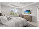 Comfortable bedroom with a TV, light-colored decor, a ceiling fan, and shuttered windows for ample natural light at 6295 Crested Eagle Ln, Nokomis, FL 34275