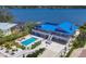Aerial view of a home with a blue roof, poolside lounge chairs, and boat dock access at 7985 Manasota Key Rd, Englewood, FL 34223