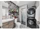 Modern bathroom featuring a stacked washer and dryer, glass shower, and mosaic tile accent wall at 7985 Manasota Key Rd, Englewood, FL 34223