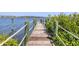 Dock on the water lined with green posts, rope, and foliage at 7985 Manasota Key Rd, Englewood, FL 34223