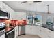 Well-lit kitchen featuring stainless steel appliances, white cabinets, and red backsplash at 7985 Manasota Key Rd, Englewood, FL 34223