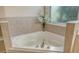 Corner bathtub with neutral tile surround and decorative vase of flowers at 8019 Indigo Ridge Ter, Bradenton, FL 34201