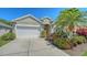 Charming exterior of a home with a two-car garage, driveway, manicured lawn, and mature tropical plants at 8019 Indigo Ridge Ter, Bradenton, FL 34201