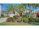 Charming home featuring a red front door and lush tropical landscaping with mature palms and flowering shrubs at 8019 Indigo Ridge Ter, Bradenton, FL 34201