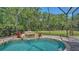 Enclosed in-ground pool featuring a rock waterfall, brick-style flooring and landscaped backyard at 8019 Indigo Ridge Ter, Bradenton, FL 34201