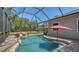 Backyard pool featuring a rock waterfall, surrounding patio, screened-in enclosure, and lush landscaping at 8019 Indigo Ridge Ter, Bradenton, FL 34201