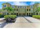 Charming green townhouse exterior featuring well-manicured landscaping, individual driveways, and lush palm trees at 8943 White Sage Loop, Lakewood Ranch, FL 34202
