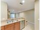 Open kitchen with stainless steel dishwasher, sink, countertop, and view of open living space with wood floors at 8943 White Sage Loop, Lakewood Ranch, FL 34202