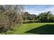 Backyard view overlooking a lush green lawn and serene pond with trees in the background, offering a peaceful setting at 9112 63Rd E Ct, Parrish, FL 34219