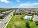 Aerial view showcases a well-manicured community with a pool and clubhouse, surrounded by green lawns and homes at 10860 79Th E St, Parrish, FL 34219