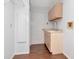 Bright laundry room with wood-look tile flooring, cabinets, utility sink, and a white entry door at 1310 91St Nw Ct, Bradenton, FL 34209