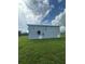 View of the backyard, showcasing the home's light blue siding and well-maintained lawn at 14343 Myakka Ave, Port Charlotte, FL 33953