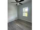 Small bedroom with a ceiling fan, grey wood floors, and a window at 14343 Myakka Ave, Port Charlotte, FL 33953