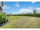 Large backyard with lush green grass, a black metal fence, and tidy shrubbery at 16119 Paynes Mill Dr, Bradenton, FL 34211