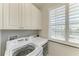 Laundry room with washer, dryer, window with plantation shutters and ample cabinets at 1918 Massachusetts Ave, Englewood, FL 34224