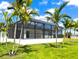Back exterior showcasing the screened-in pool area with palm trees at 217 Rotonda S Blvd, Rotonda West, FL 33947
