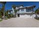 Beautiful exterior of home featuring a multi-car garage, balconies, landscaping, and palm trees at 222 Willow Ave, Anna Maria, FL 34216