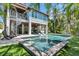 A resort-style pool and spa are the focal point, complemented by an outdoor spiral staircase and verdant landscaping at 222 Willow Ave, Anna Maria, FL 34216