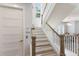Bright staircase featuring white risers, wooden handrails, and a view to the chandelier in the dining room at 222 Willow Ave, Anna Maria, FL 34216