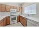 Well-lit kitchen featuring wooden cabinets, white appliances, tiled floors and a bright window at 238 Cape Harbour Loop # 104, Bradenton, FL 34212