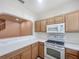 Well-lit kitchen featuring wooden cabinets, white appliances, tiled floors, and a view of the staircase at 238 Cape Harbour Loop # 104, Bradenton, FL 34212
