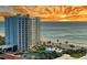 Coastal condo building with beach access, tennis court, and pool overlooking the ocean during a vibrant sunset at 2525 Gulf Of Mexico Dr # 3F, Longboat Key, FL 34228