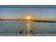 Sunset view of a waterway with a bridge, palm trees, and docks from the balcony at 280 Golden Gate Pt # 600, Sarasota, FL 34236